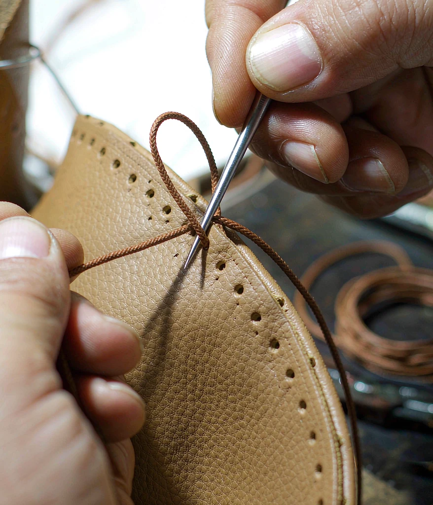 Hand stitching a leather bag edge with waxed thread