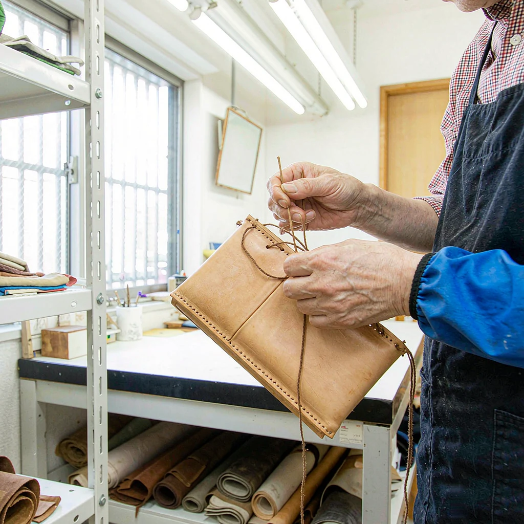Artisan hands stitching a leather bag in the workshop